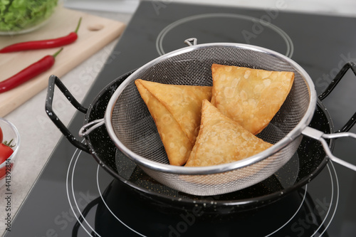 Fototapeta Naklejka Na Ścianę i Meble -  Heating up samosas on electric stove, closeup