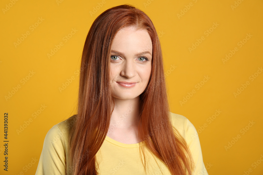Candid portrait of happy young woman with charming smile and gorgeous red hair on yellow background Candid portrait of happy young woman with charming smile and gorgeous red hair on yellow background