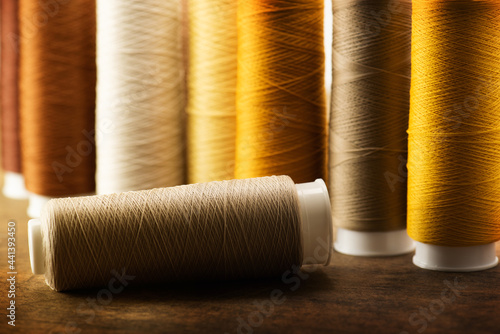 brown, beige, tan colored sewing thread spools on a old work table. Shallow depth of field. Intentionally shot in low key.
 photo