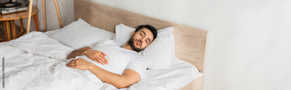 Fototapeta premium Young man in white t-shirt sleeping on bed, banner