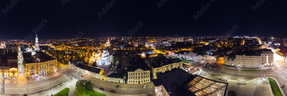 City center aerial wide panorama. Konstytutsii Square, historical museum, Sumska St, Cathedrals, Svyato-Pokrovskyy Monastyr landmarks in Kharkiv, Ukraine. Night lights illuminated