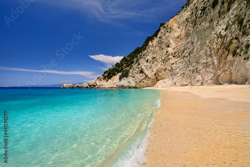 Sandy beach with rocky mountains and clear blue sea along the northern coast of the Greek island of Ithaca in the Ionian Sea