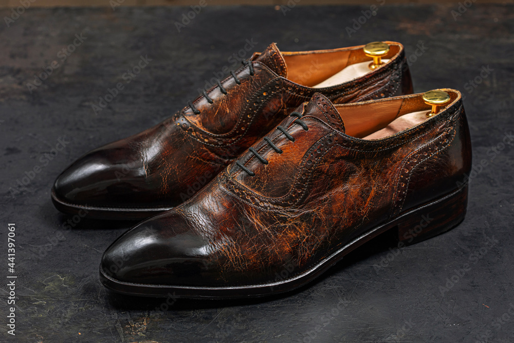 Leather brown men's shoes on a dark wooden background, angle view. Classic men's shoes.