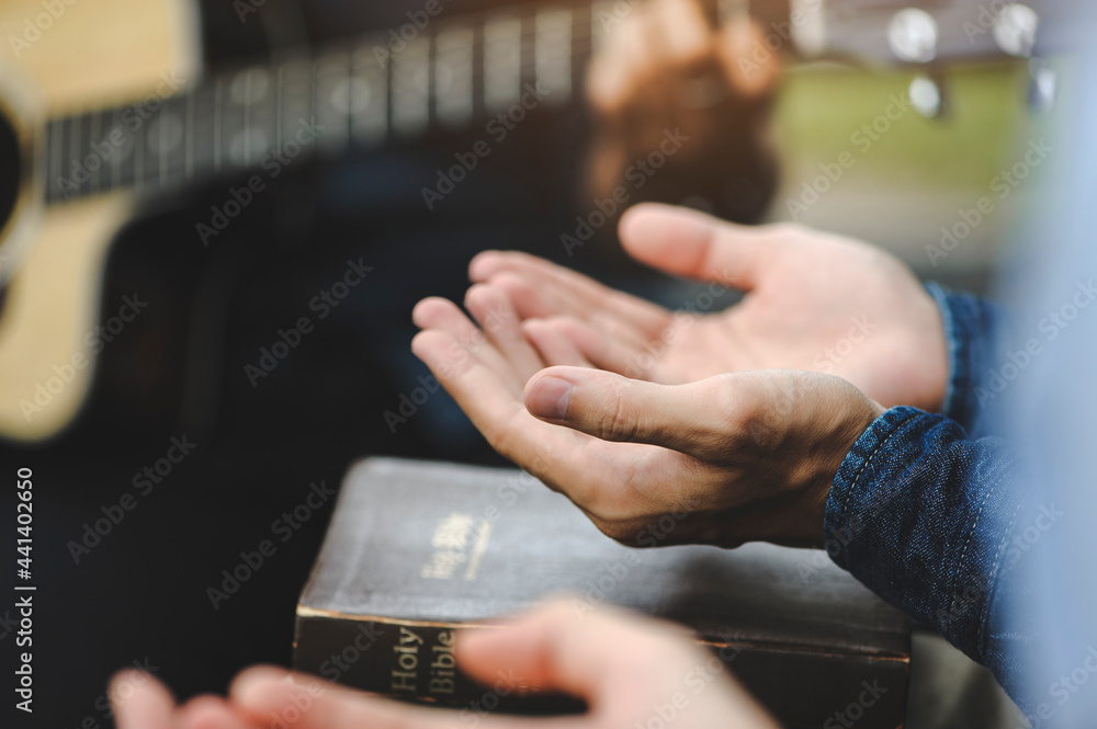 Christian family groups holding hands praying with Holy Bible. and play guitar to sing worship thanksgiving praise and seek the blessings of God with belief. reading Bible and sharing the gospel