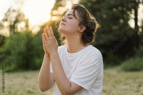 Foto Woman closed her eyes, praying in a field during beautiful sunset