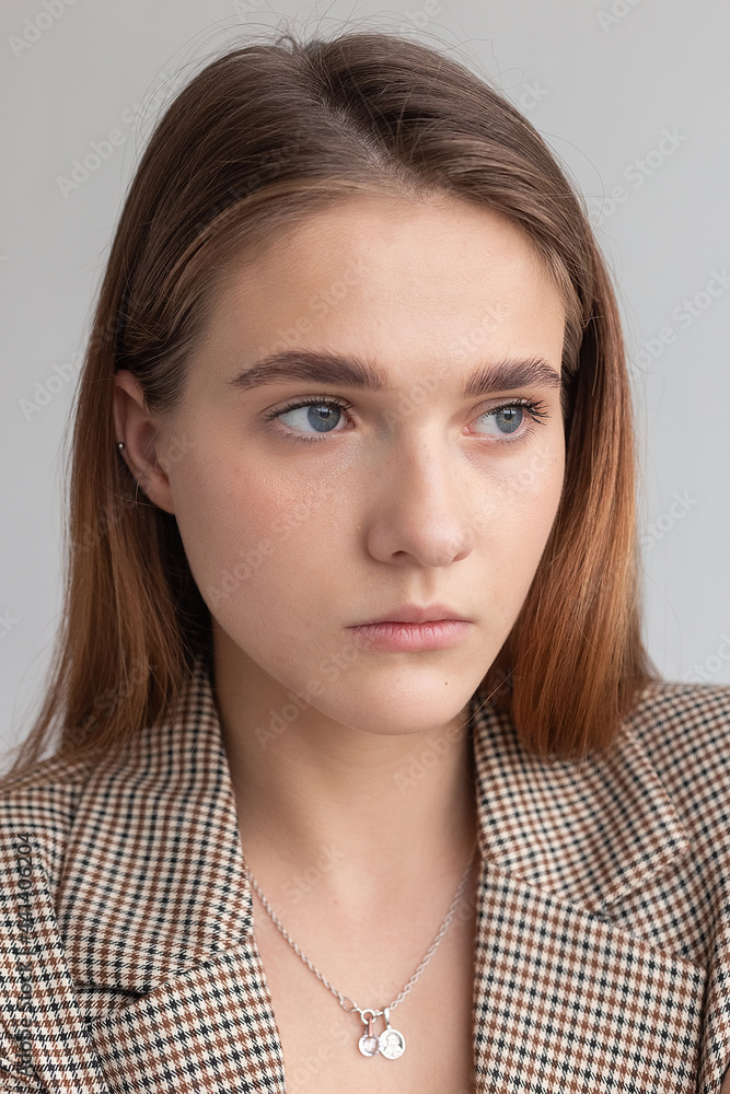 portrait of young attractive caucasian woman with long brown hair in suit jacket and chain on her neck. skinny pretty lady posing on white or grey background at studio. model tests of beautiful lady portrait of young attractive caucasian woman with long brown hair in suit jacket and chain on her neck. skinny pretty lady posing on white or grey background at studio. model tests of beautiful lady