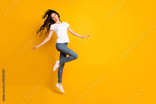 Full length body size view of lovely cheerful girl jumping having fun dancing isolated over bright yellow color background
