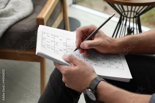 Φωτογραφία Man solving sudoku puzzle at home, closeup