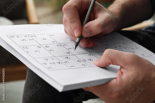 Photos Man solving sudoku puzzle indoors, closeup view