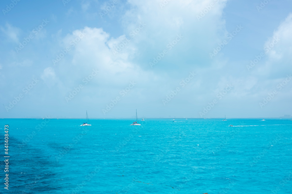 Two white catamaran sailing in the turquoise sea of the Mexican Caribbean, Isla Mujeres. In the background the blue sky partially cloudy