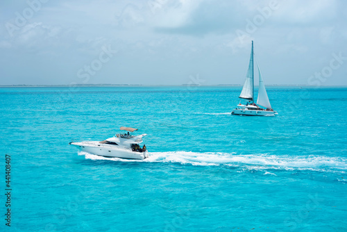 A luxury yacht and catamaran sail the turquoise Mexican Caribbean Sea near the coast of Cancun and Isla Mujeres.
