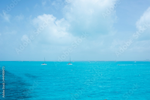 Two white catamaran sailing in the turquoise sea of the Mexican Caribbean  Isla Mujeres. In the background the blue sky partially cloudy