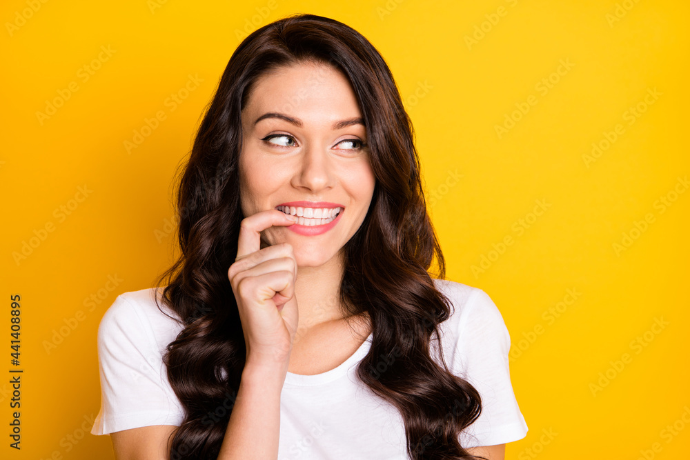 Photo of dreamy cute young woman look empty space bite finger teeth isolated on yellow color background Photo of dreamy cute young woman look empty space bite finger teeth isolated on yellow color background