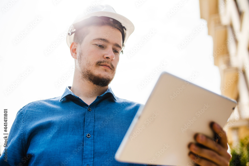 An engineer or an architect in a helmet with a tablet in his hands. Monitoring the progress of construction. A man in a hard hat. An engineer or an architect in a helmet with a tablet in his hands. Monitoring the progress of construction. A man in a hard hat.