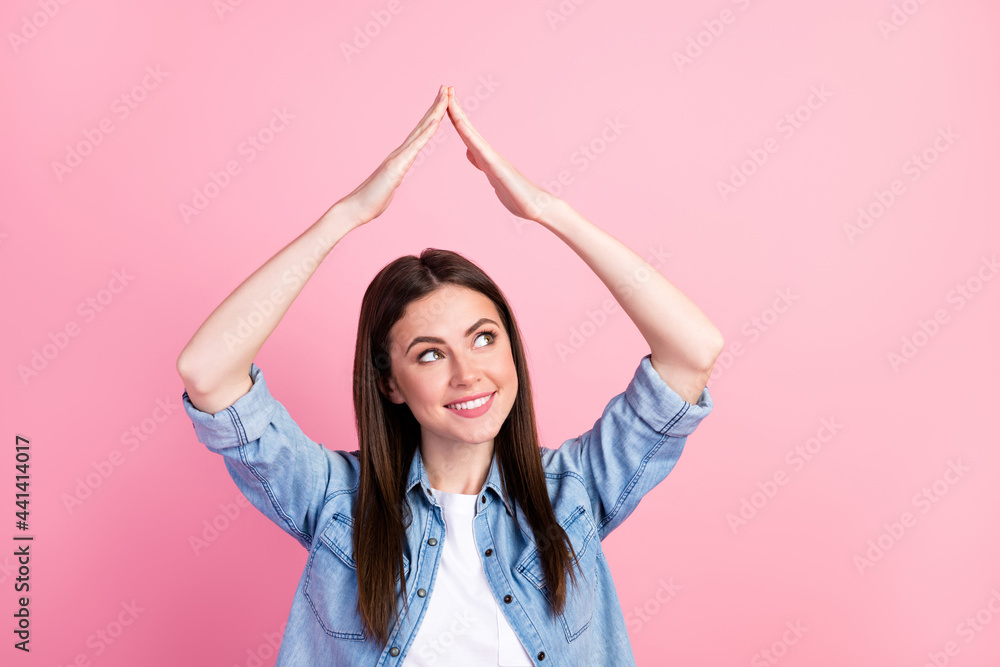 Photo of dreamy nice happy young woman look empty space hold hands shape house above head isolated on pink color background
