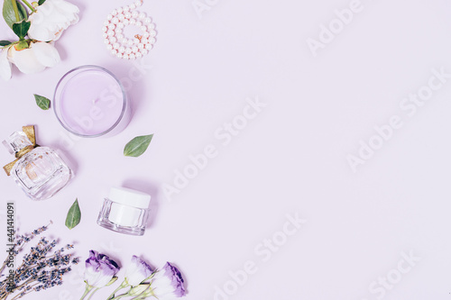 Feminine accessories, cosmetics and perfume next to flowers © progressman