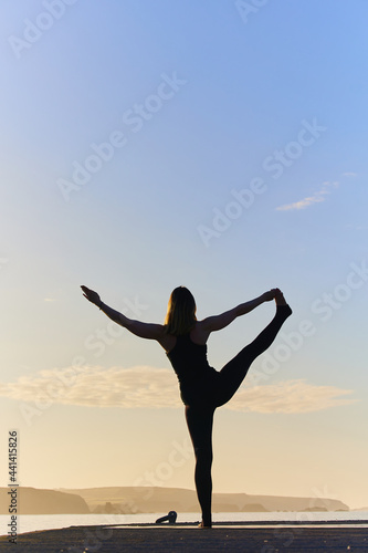 spectacular yoga asana in silhouette of an attractive woman near the ocean at a sunrise
