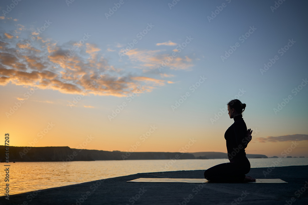 silhouette of thin woman stretching and doing yoga pose. healthy lifestyle concept and sport