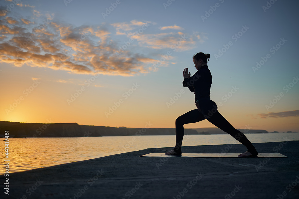 silhouette of woman practicing yoga in backlight
