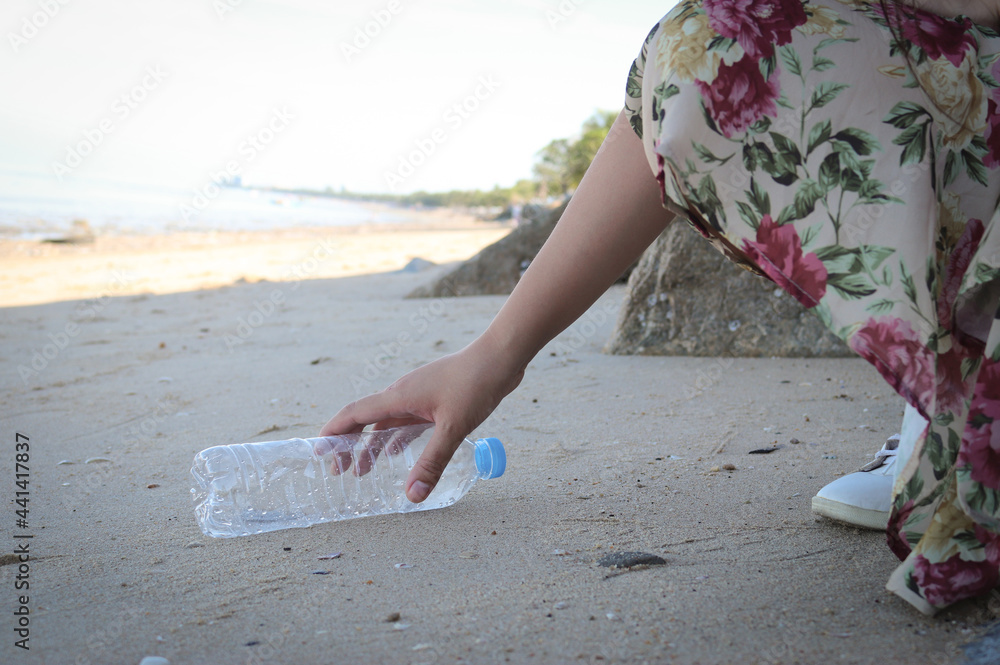 Fotografie Hand picking up plastic bottle cleaning on the beach