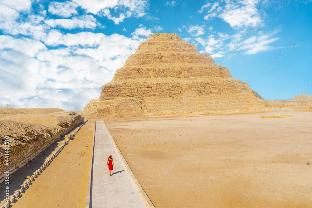 Φωτογραφία A young girl in a red dress walking in the Stepped Pyramid of Djoser, Saqqara