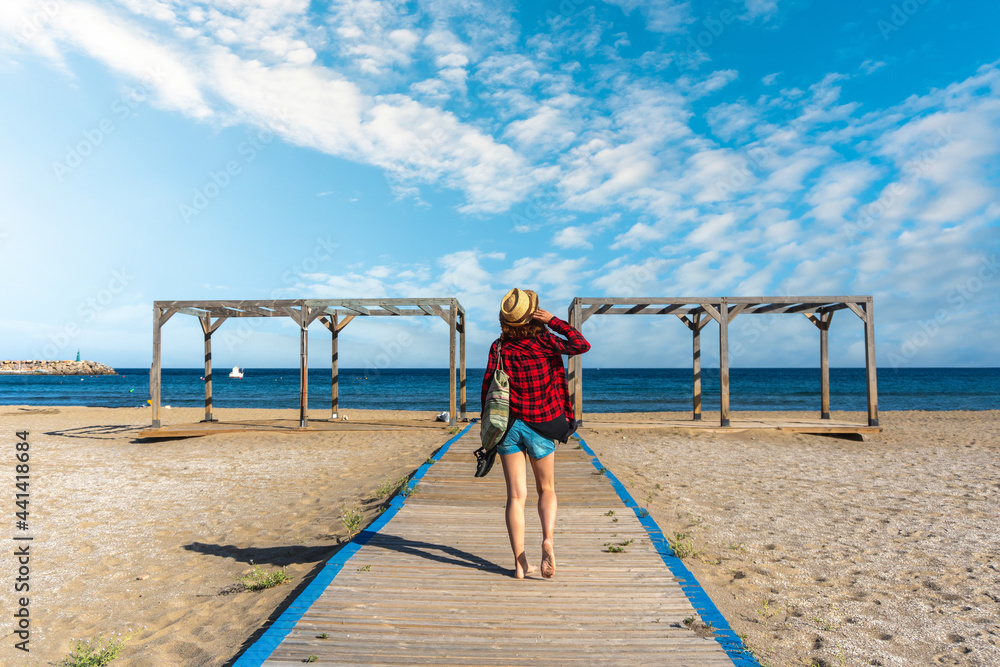 A young tourist on the wooden walkway of San Jose beach in the town of Nijar, Almería. Andalusian coast in Cabo de Gata. Spain A young tourist on the wooden walkway of San Jose beach in the town of Nijar, Almería. Andalusian coast in Cabo de Gata. Spain