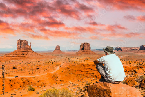 A young boy with white t-shirt sitting in the center of the photo on a stone in the Monument Valley National Park in the visitor center. Utah