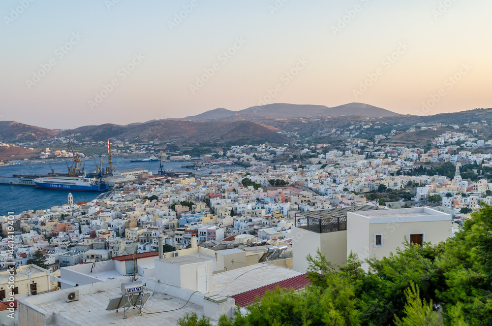 Panoramic View of Ermoupolis City, Syros, Greece at Sunset. Beautiful Bay and View of the Aegean Sea, Mountains and Sky. Traditional White Houses, Villas and Port. 