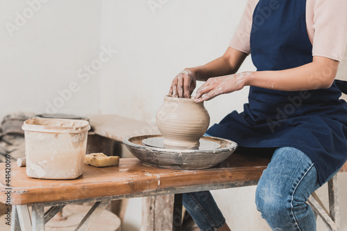 partial view of young african american woman modeling wet clay pot on wheel in pottery