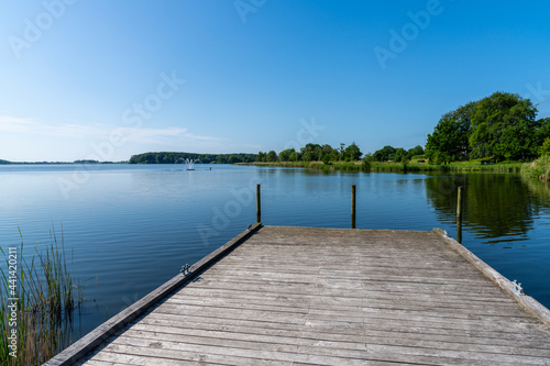 wooden dock leads out into a calm lake with dark blue water
