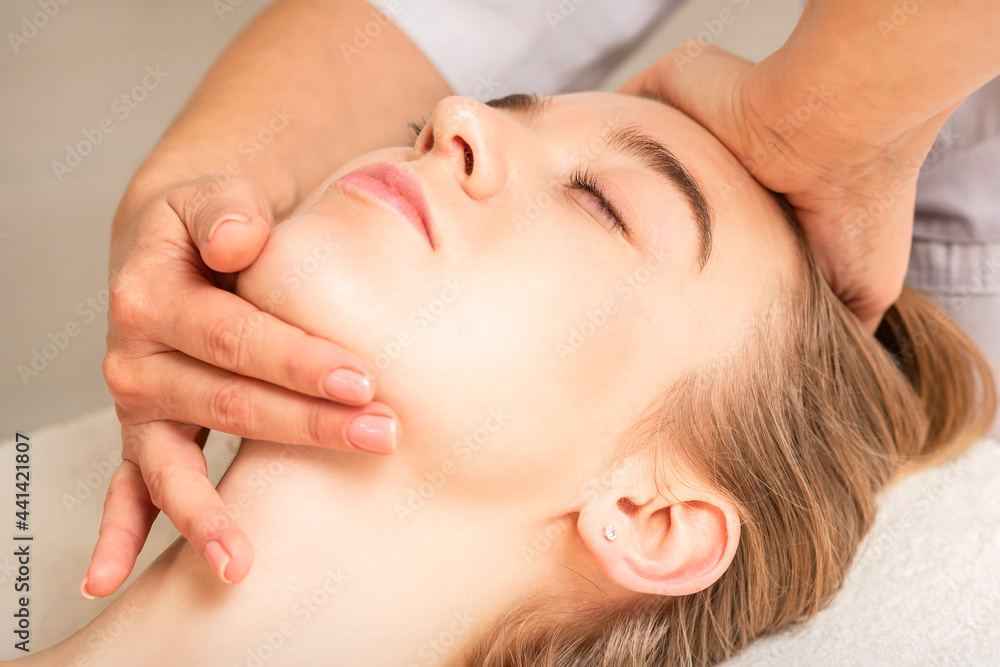 Young caucasian woman receiving a head and chin massage in a spa medical center