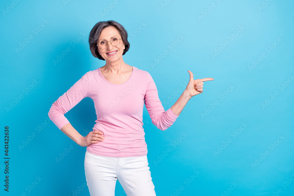 Photo of happy excited cheerful lovely woman in glasses point finger copyspace advertisement isolated on blue color background Photo of happy excited cheerful lovely woman in glasses point finger copyspace advertisement isolated on blue color background