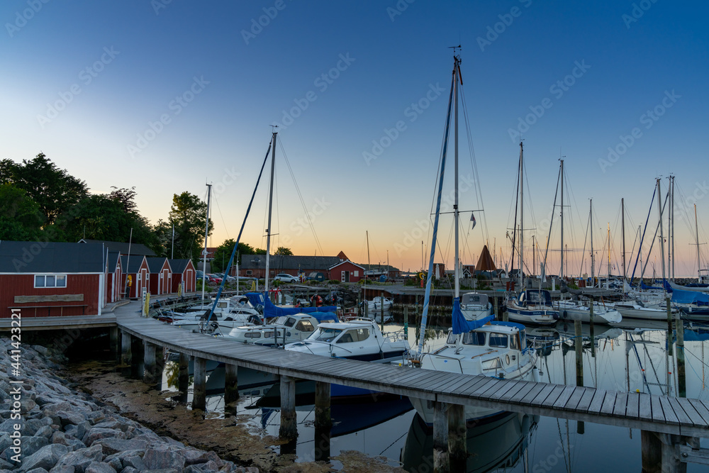 the picturesque small marina at Lundeborg with many sailboats and colorful hosues at sunset