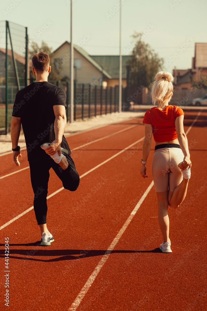 girl and a guy doing a warm-up before sports exercises at the school stadium