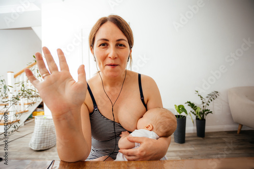 Portrait of mother breastfeeding baby during online meeting