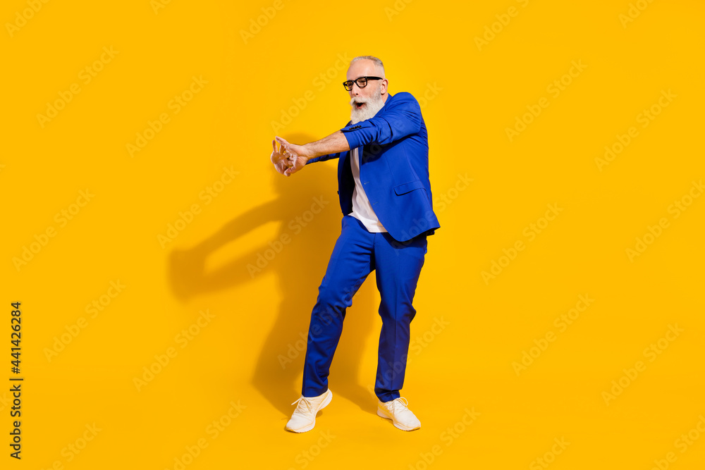 Full size profile photo of funky grey beard old man dance wear spectacles blue jacket isolated on yellow background Full size profile photo of funky grey beard old man dance wear spectacles blue jacket isolated on yellow background