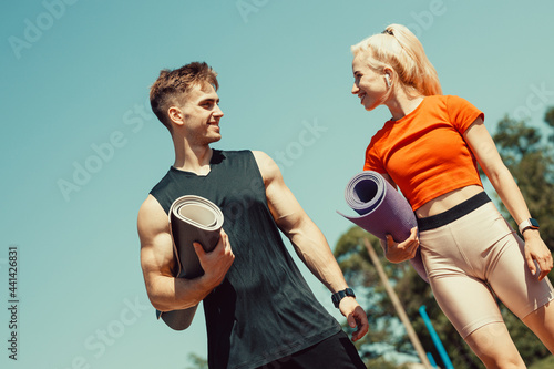 young couple walking down the street with sports mats in their hands