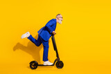 Full size profile side photo of happy excited crazy mature man look copyspace riding scooter isolated on yellow color background