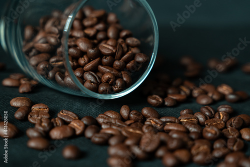 Dark roasted coffee beans with glass on black background