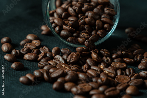 Dark roasted coffee beans with glass on black background