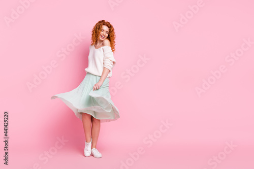 Full length body size photo of red hair woman smiling in skirt dancing spinning at party isolated on pastel pink color background