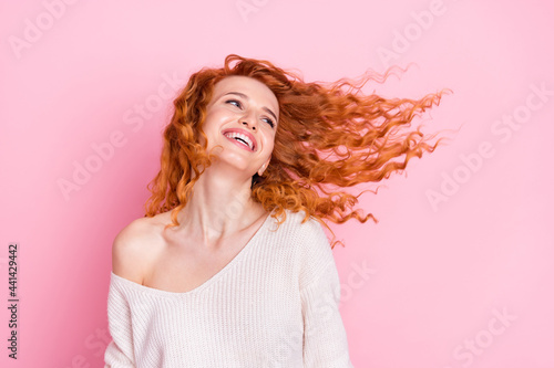 Photo portrait of young girl laughing with hair flying in air looking blank space isolated pastel pink color background