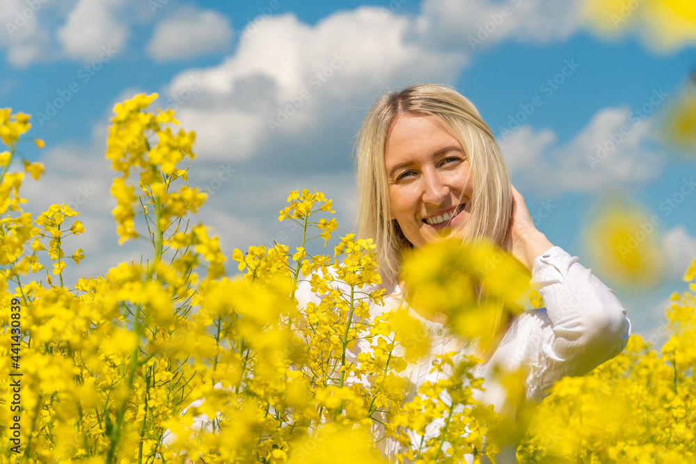 Portrait of a beautiful happy young blonde woman in a white shirt in a rapeseed field on a sunny day Portrait of a beautiful happy young blonde woman in a white shirt in a rapeseed field on a sunny day