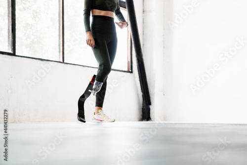 Young woman with prosthesis standing while working out indoors
