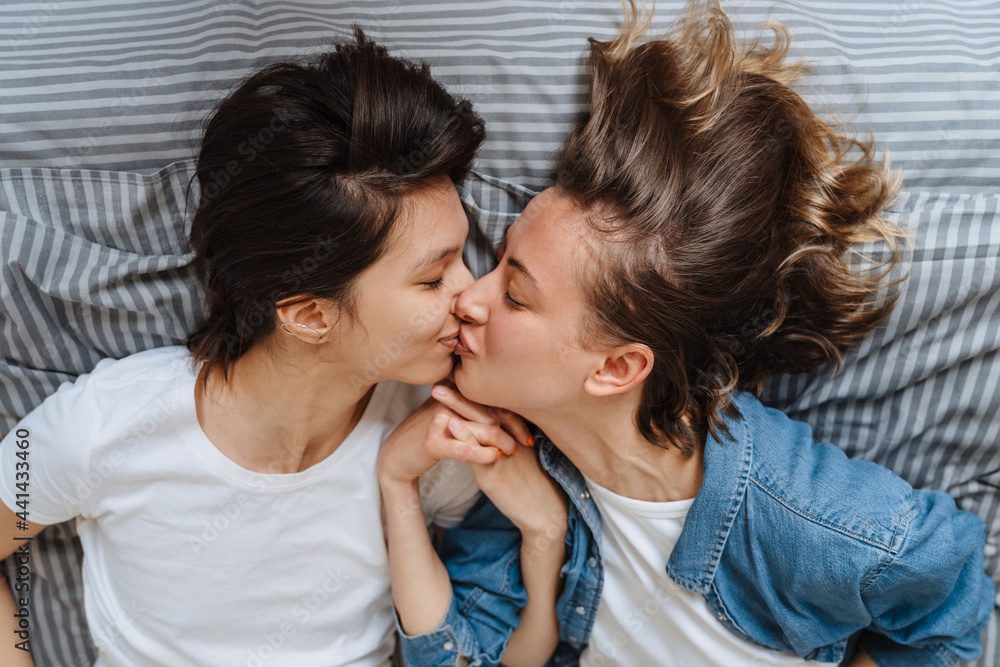 A portrait of the kissing lesbian couple girls holding hands on the bed A portrait of the kissing lesbian couple girls holding hands on the bed