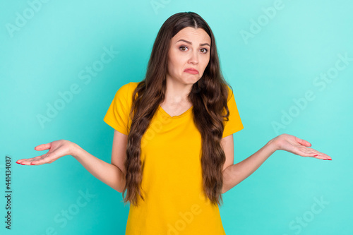 Photo of unsure millennial lady shrug shoulders wear yellow t-shirt isolated on vivid teal color background