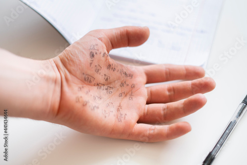 hand with formulas on the exam  cheating note on the palm during study