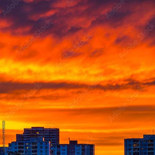 Burning sky over city buildings at sunset