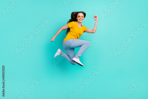 Full body profile photo of funky young lady jump wear eyewear yellow t-shirt jeans isolated on teal color background