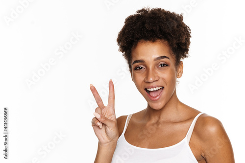 Young black woman in tank top smiling and gesturing at camera